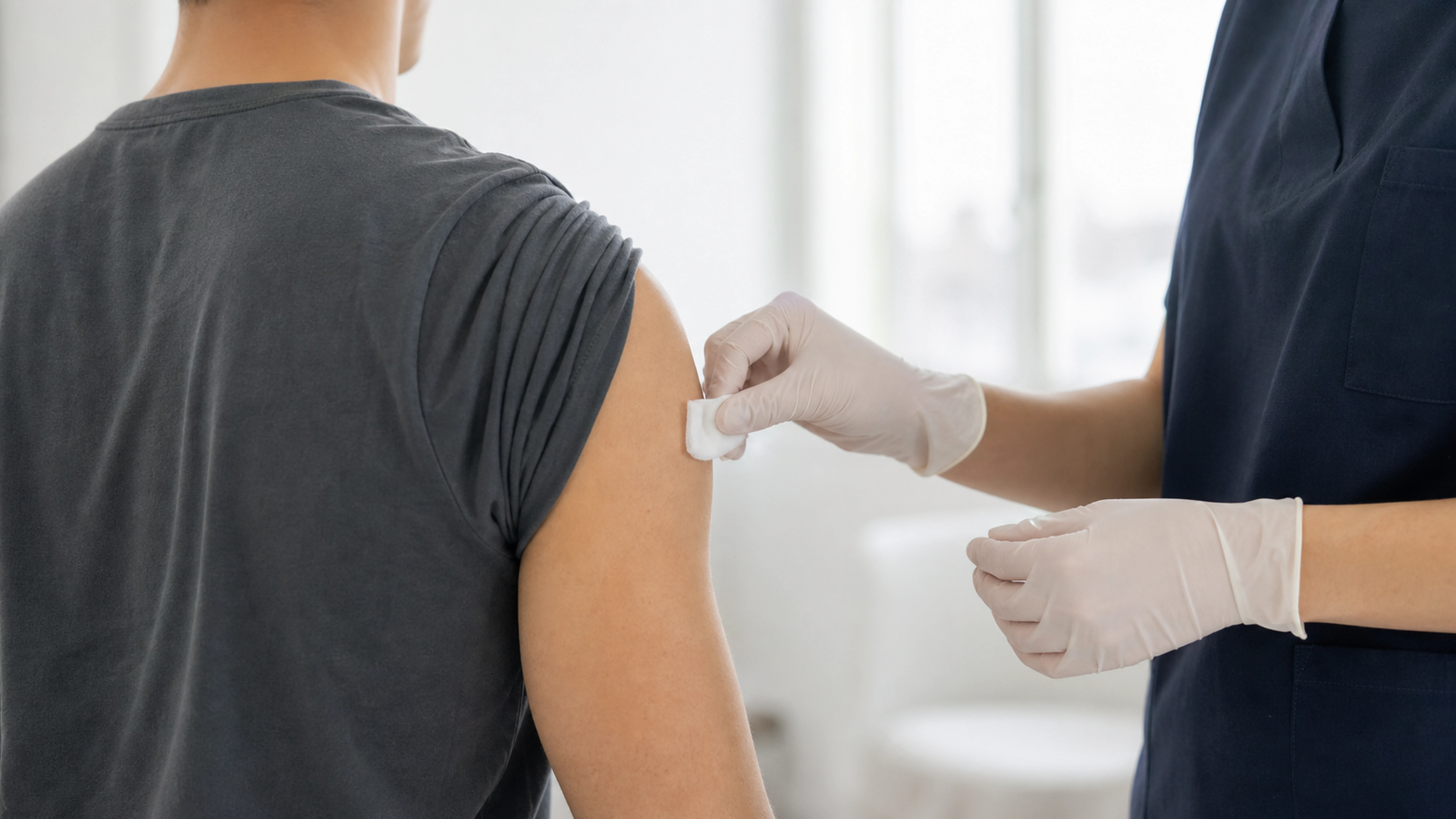 Une professionnelle de santé applique une compresse sur le bras d’un adulte après une vaccination